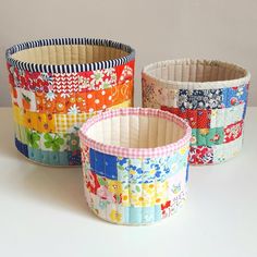 three colorful baskets sitting on top of a white table next to each other with different designs