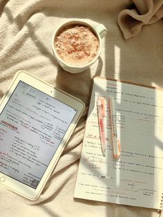 an ipad, pen and cup of coffee sitting on a blanket next to a notebook