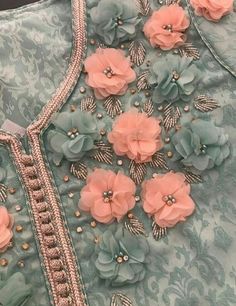 a dress with flowers on it and beading around the neck, along with pearls