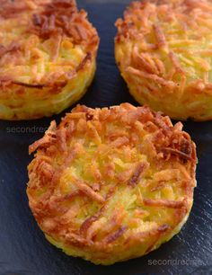 three mini quiches with bacon on top are sitting on a black plate, ready to be eaten