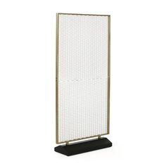 a white and gold metal screen on a black stand with an open end, in front of