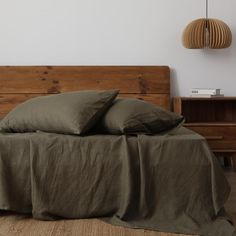 a bed with two pillows on top of it next to a wooden headboard and night stand