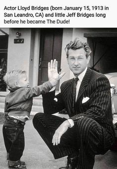 a man in a suit and tie kneeling down next to a little boy with his hand up