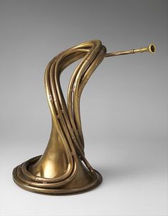 a gold colored sculpture with curved curves on it's sides and a white background