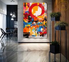 an abstract painting hangs on the wall next to a dining room table with chairs and potted plants