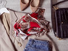 clothes and shoes laid out on a bed next to a handbag, wallet, purse