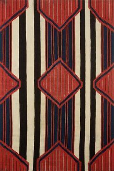 a red, black and white striped rug with an abstract design on the bottom corner