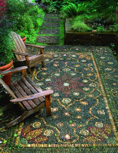 two wooden chairs sitting on top of a rug in the middle of a garden area