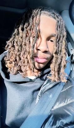 a man with dreadlocks sitting in the back seat of a car wearing a hoodie