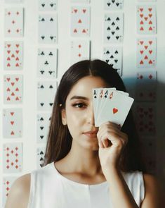 a woman holding four playing cards in front of her face