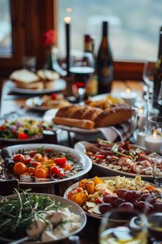 a table filled with lots of different types of food and wine glasses on top of it