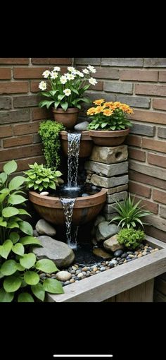 a water fountain surrounded by plants and rocks in front of a brick wall with text overlay