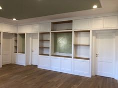 an empty room with white cabinets and wood floors