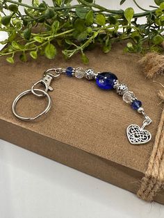 a blue beaded keychain sitting on top of a wooden box next to a plant