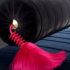 a black cushion with pink tassels on it