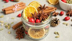 an assortment of spices and fruits in a glass jar with cinnamons, orange slices, star anise, cloves