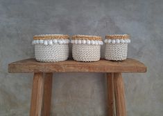 three white baskets sitting on top of a wooden table