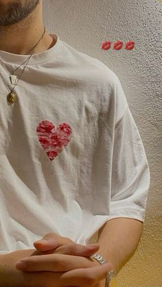 a man wearing a white t - shirt with a heart on it's chest