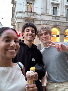 three young people posing for the camera with an ice cream cone in front of them