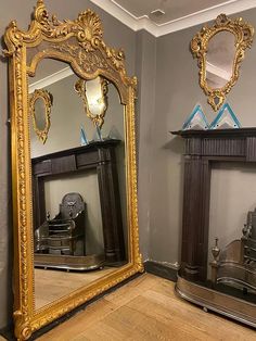 two large mirrors sitting next to each other on top of a wooden floor in front of a fireplace