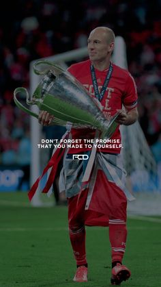 a man holding a trophy on top of a soccer field with the words, don't forget the promise that you made to yourself