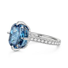 This is a stunning blue stone ring that exudes elegance and sophistication. The centre of the ring is set with a large, captivating blue stone that commands attention with its deep, enchanting hue. The sparkling centre stone is also set with a hidden halo of smaller round stones, and the glittering stone-set band adds to the brilliance of this chic ring. The smooth and delicate design ensures a comfortable fit while showcasing the beauty of the central blue stone.Carat Weight: 6.29 ctStone Size: 10*12 mmStone Type: Jeulia® StoneNumber of Stones: 1 Stone Color: Aquamarine BlueStone Shape: Fat OblongCarat Weight: 1.381 ctStone Size: 1,1.2,1.7,0.8 mmStone Type: Jeulia® StoneNumber of Stones: 68 Stone Color: Diamond WhiteStone Shape: RoundWeight: 2.9 gWidth: 1.9 mmHeight: 10 mmThickness: 1.5 m Blue Cushion Cut Halo Ring With Center Stone, Elegant Cushion Cut Topaz Ring With Gemstone Accents, Blue Cushion Cut Halo Ring Fine Jewelry, Blue Cushion Cut Halo Ring, Blue Open Ring Crystal Fine Jewelry, Blue Diamond Ring With Gemstone Accents, Elegant Blue Sapphire Ring, Cushion Cut, Elegant Blue Cushion Cut Sapphire Ring, Fine Jewelry Blue Open Diamond Ring