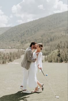 a man and woman standing next to each other while holding golf balls in their hands