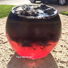 a glass filled with liquid sitting on top of a cement slab next to a car