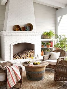 a living room filled with furniture and a fire place next to a brick fireplace surrounded by potted plants