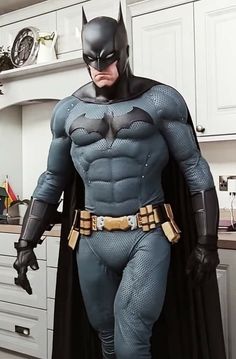 a man dressed as batman standing in a kitchen