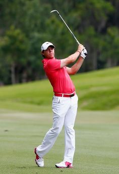 a man in red shirt and white pants playing golf