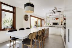 a large white kitchen with lots of counter space and chairs around the dining room table