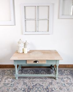 a coffee table with two candles on it in front of a white wall and blue rug