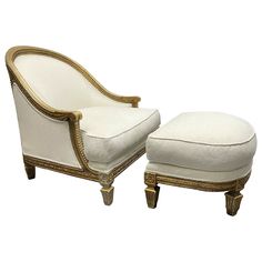 a white chair and ottoman with gold trimmings on the legs, sitting next to each other