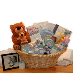 a teddy bear sitting next to a basket filled with baby items