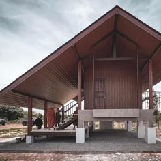 two people are standing on the porch of a small wooden building that is made out of concrete