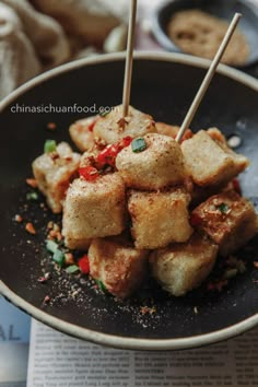 food in a bowl with chopsticks sticking out of the top and some sauce on the side