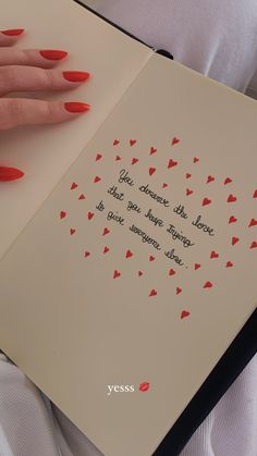 a woman's hand holding an open book with red hearts on it and the words,