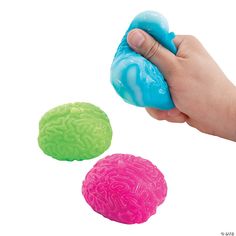 a hand is holding a soap ball and two balls are in the foreground, with one being squished