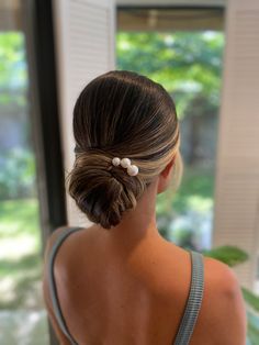 a woman with her back to the camera, wearing a gray top and pearls in her hair