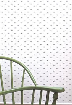 a green rocking chair sitting in front of a wall with dots on it's back