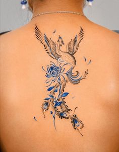 the back of a woman's neck with a bird and flowers tattoo on it