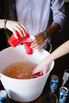 two people pouring drinks into a white bucket