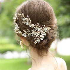 a woman wearing a bridal hair comb with flowers on it's head and leaves in her hair