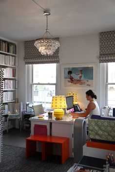 a woman sitting at a desk in front of a laptop computer on top of a table