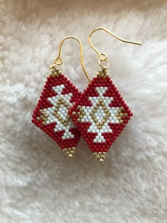 two red and white beaded earrings sitting on top of a furnishing floor