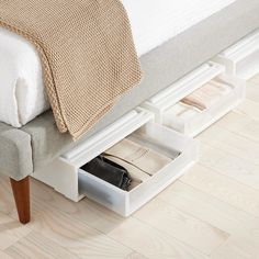 a bed with two drawers underneath it and a blanket on the headboard, next to a wooden floor