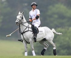 a man riding on the back of a white horse while holding a stick in his hand