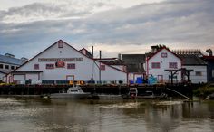 two boats are docked in front of a large white building with red trim and windows