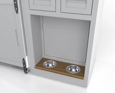 two metal bowls are in the corner of a cabinet with one door open to reveal another dog's food bowl